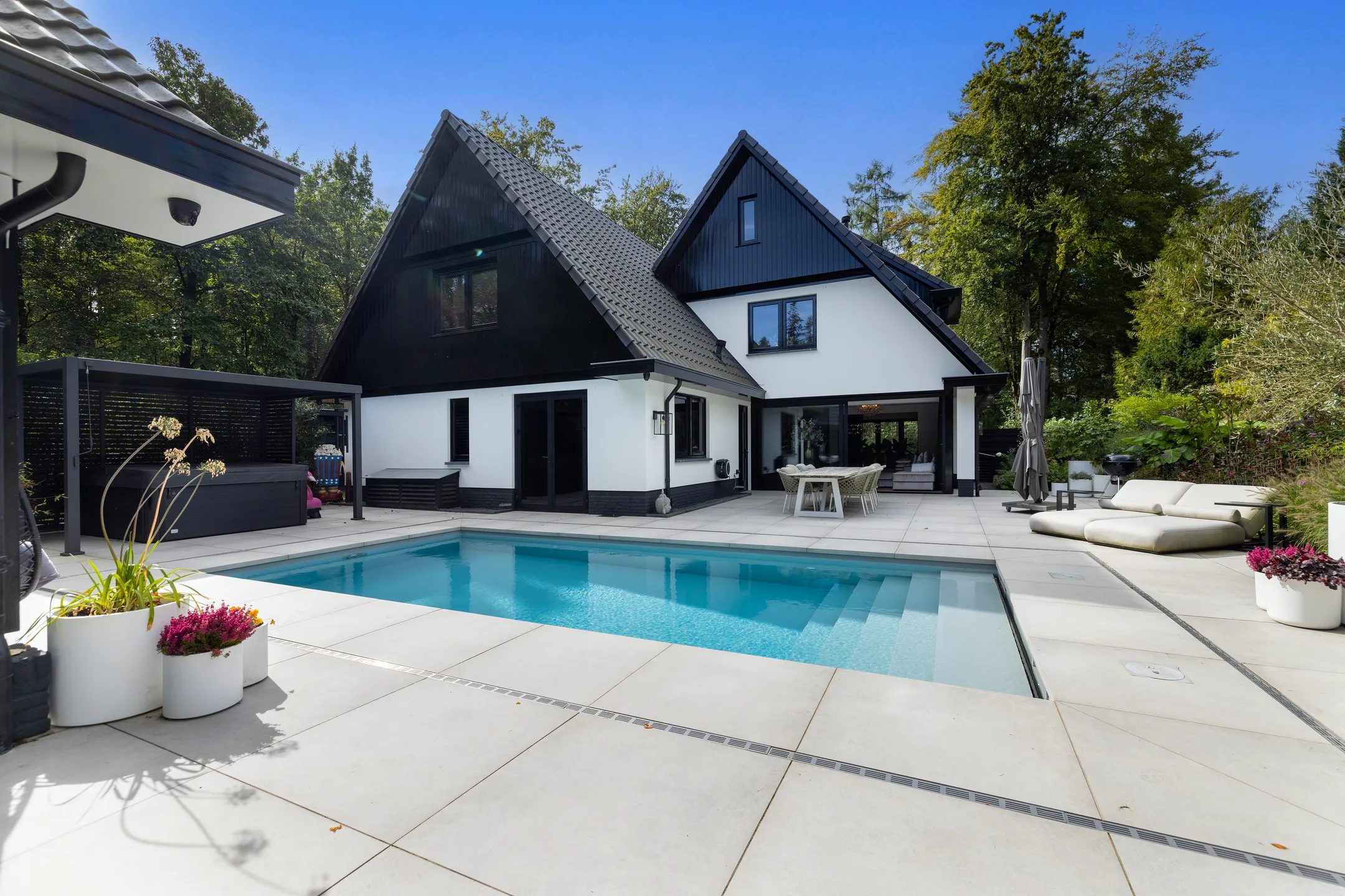 Een zwembad met jacuzzi in de tuin. 