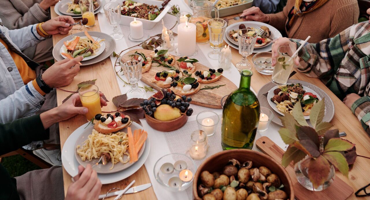 Mensen die aan een tafel zitten met allemaal verschillende gerechten op tafel.