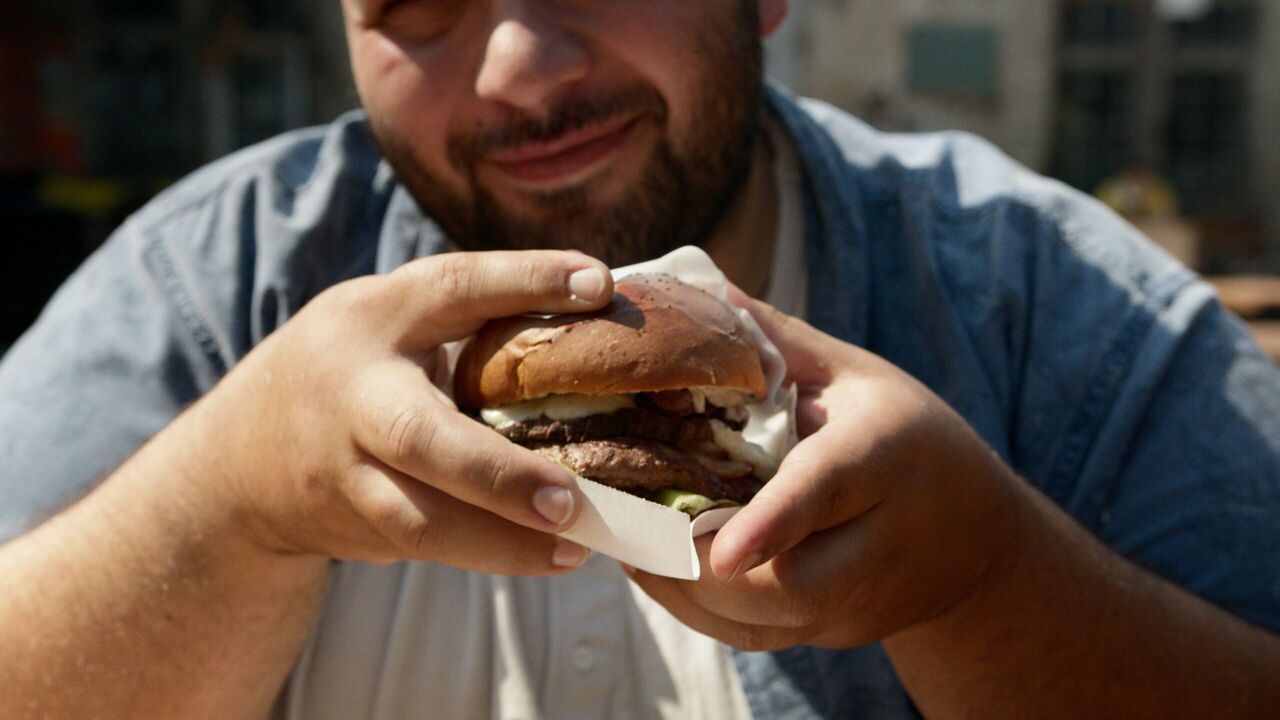 Een man die een hap uit een burger gaat nemen.