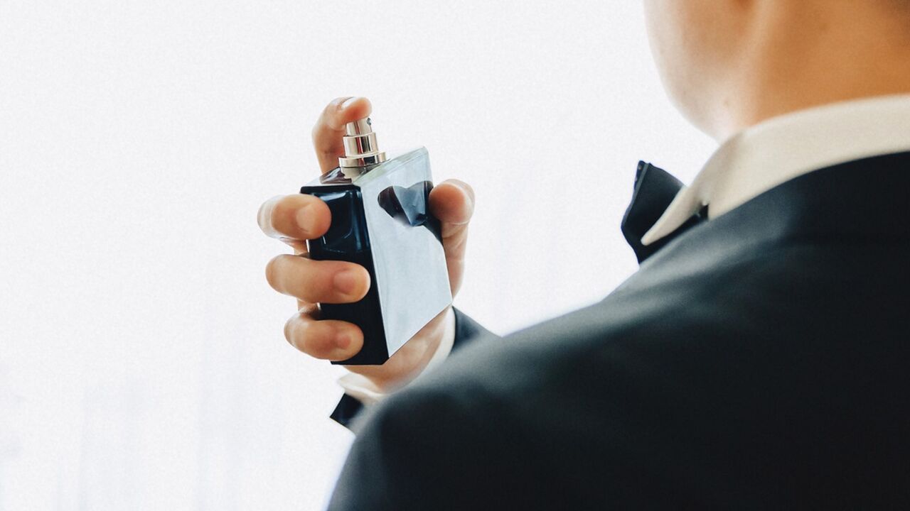 Een man die parfum in zijn eigen nek sprayt met wat Vaseline in zijn nek
