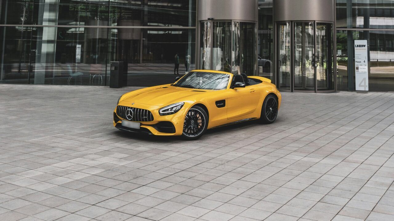 Een gele Mercedes voor een gebouw