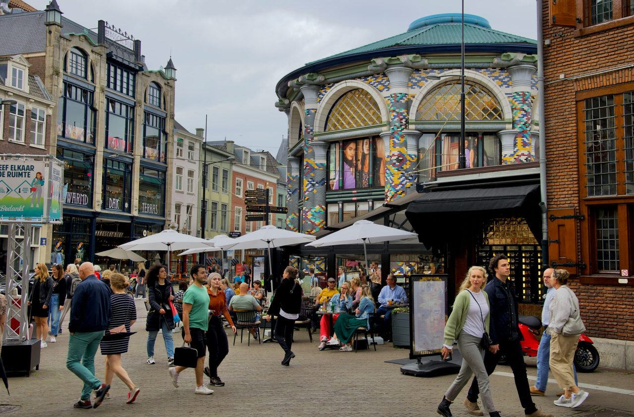 Een drukke straat in Den Haag met terrassen en veel mensen.