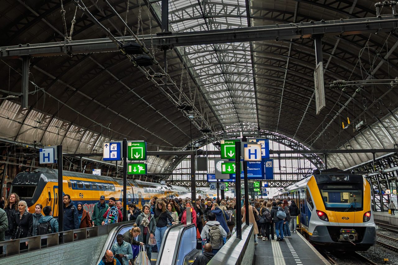 NS-treinen die wachten bij de perrons terwijl mensen uitstappen.