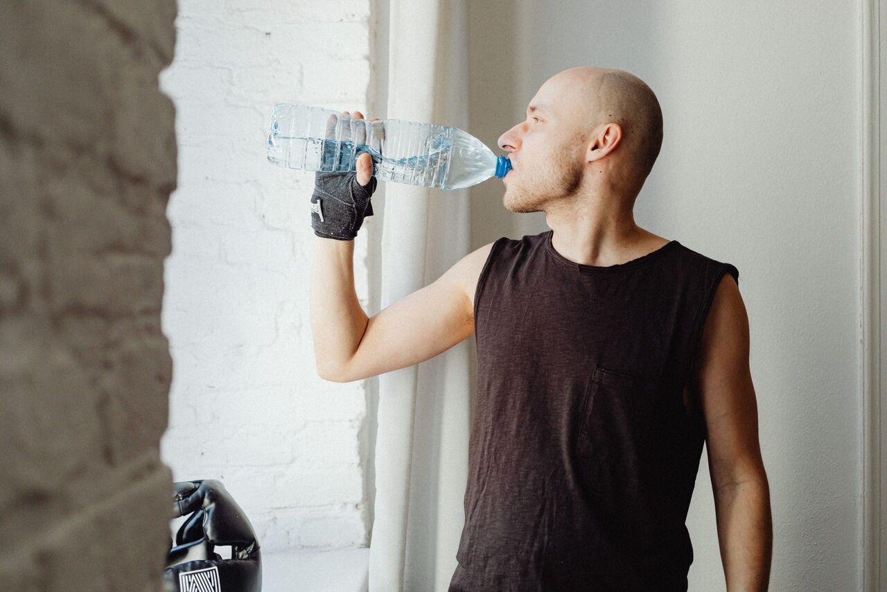 Een man die water drinkt uit een fles.