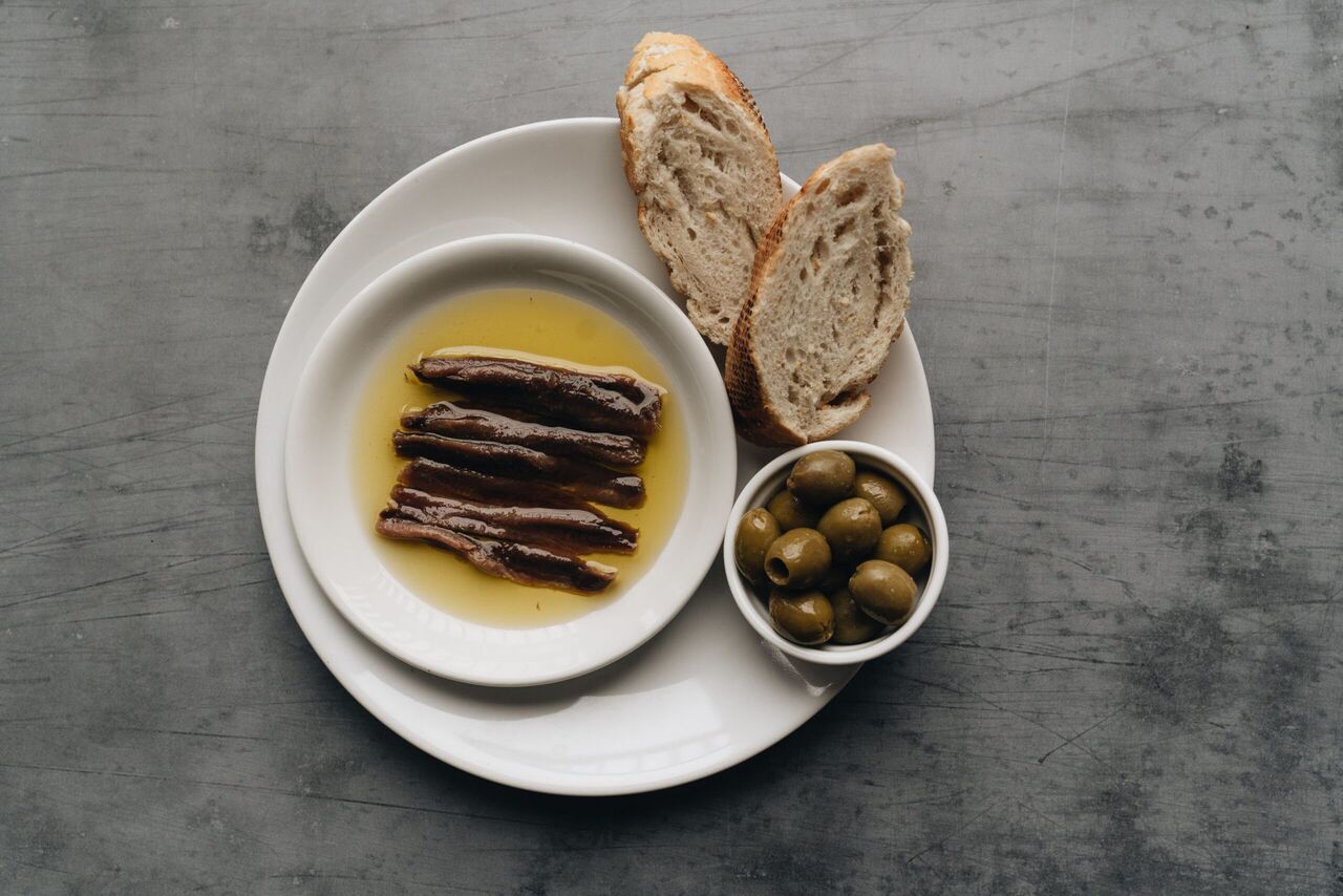 Sardientjes met brood en olijven op een bord