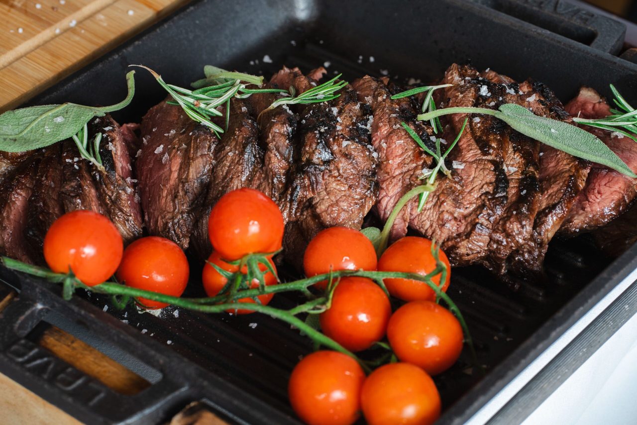 Een bord met vlees en tomaten.