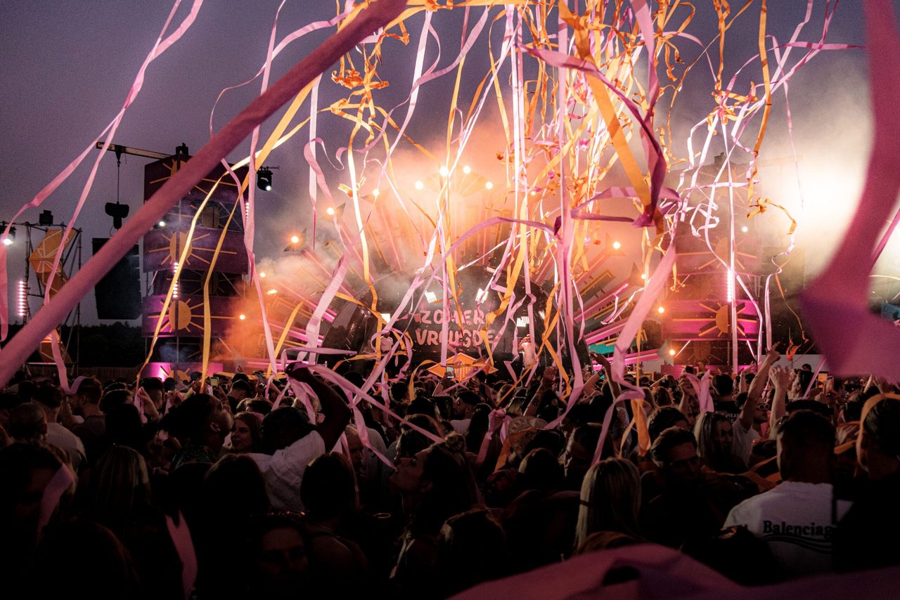 Een festival waar mensen dansen en slingers in de lucht worden geschoten. 
