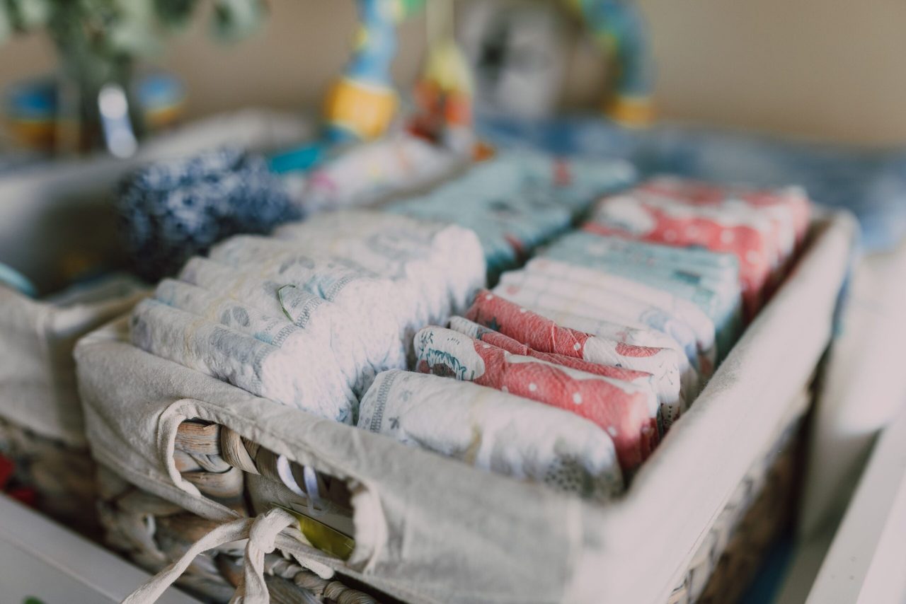 Babykleding en luiers in een mandje.