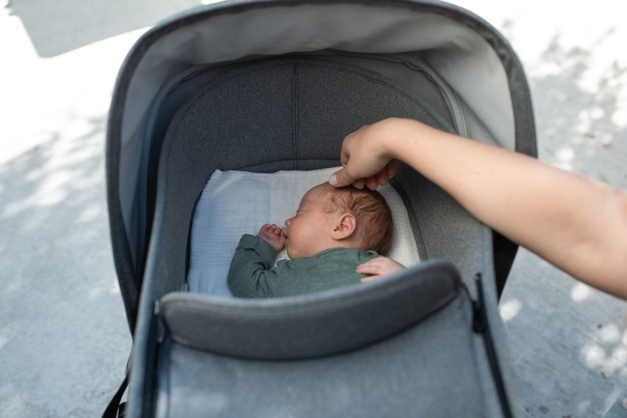 Een baby die in een kinderwagen ligt.