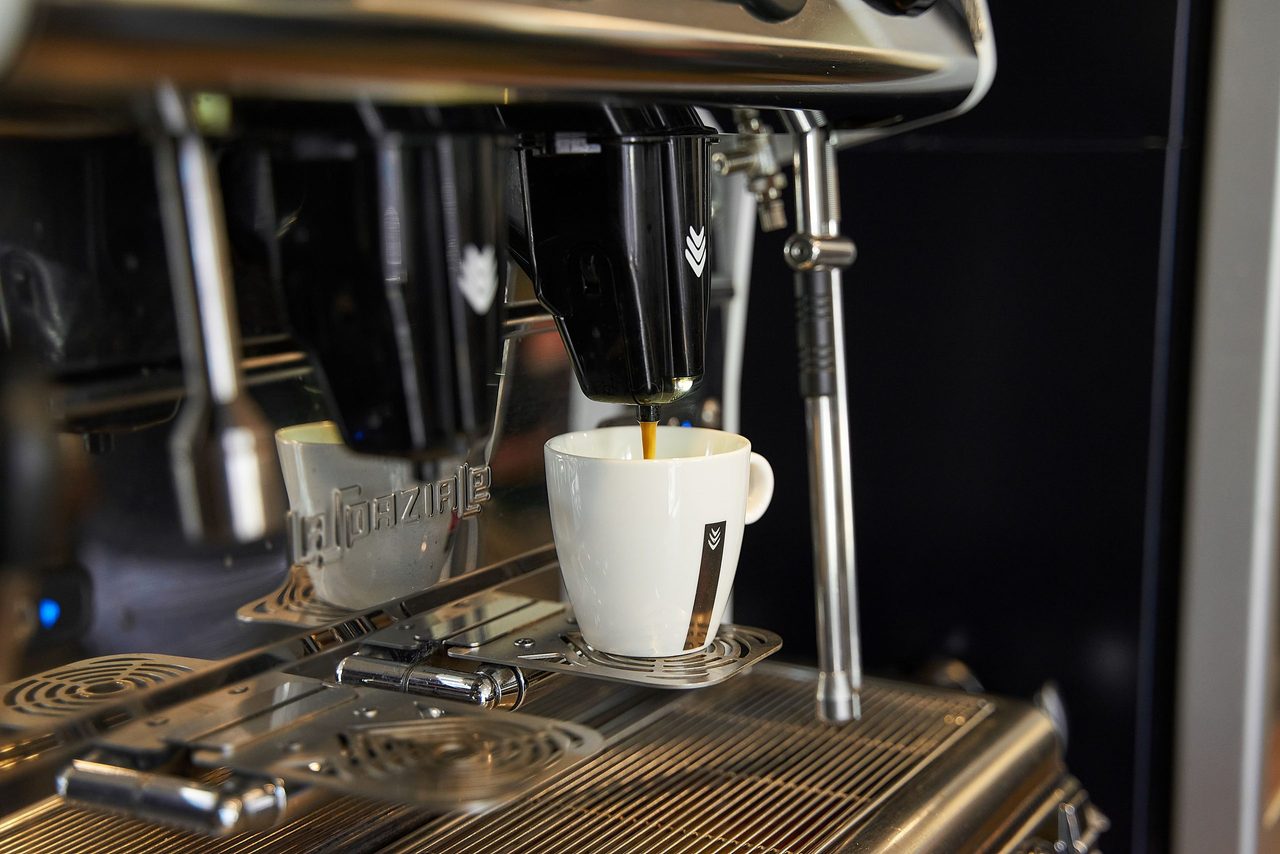 Een kopje dat staat onder een koffiezetapparaat. 
