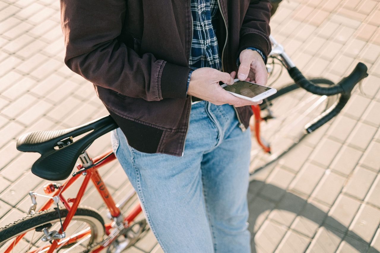 Een man die op zijn fiets zit met zijn telefoon in zijn hand.