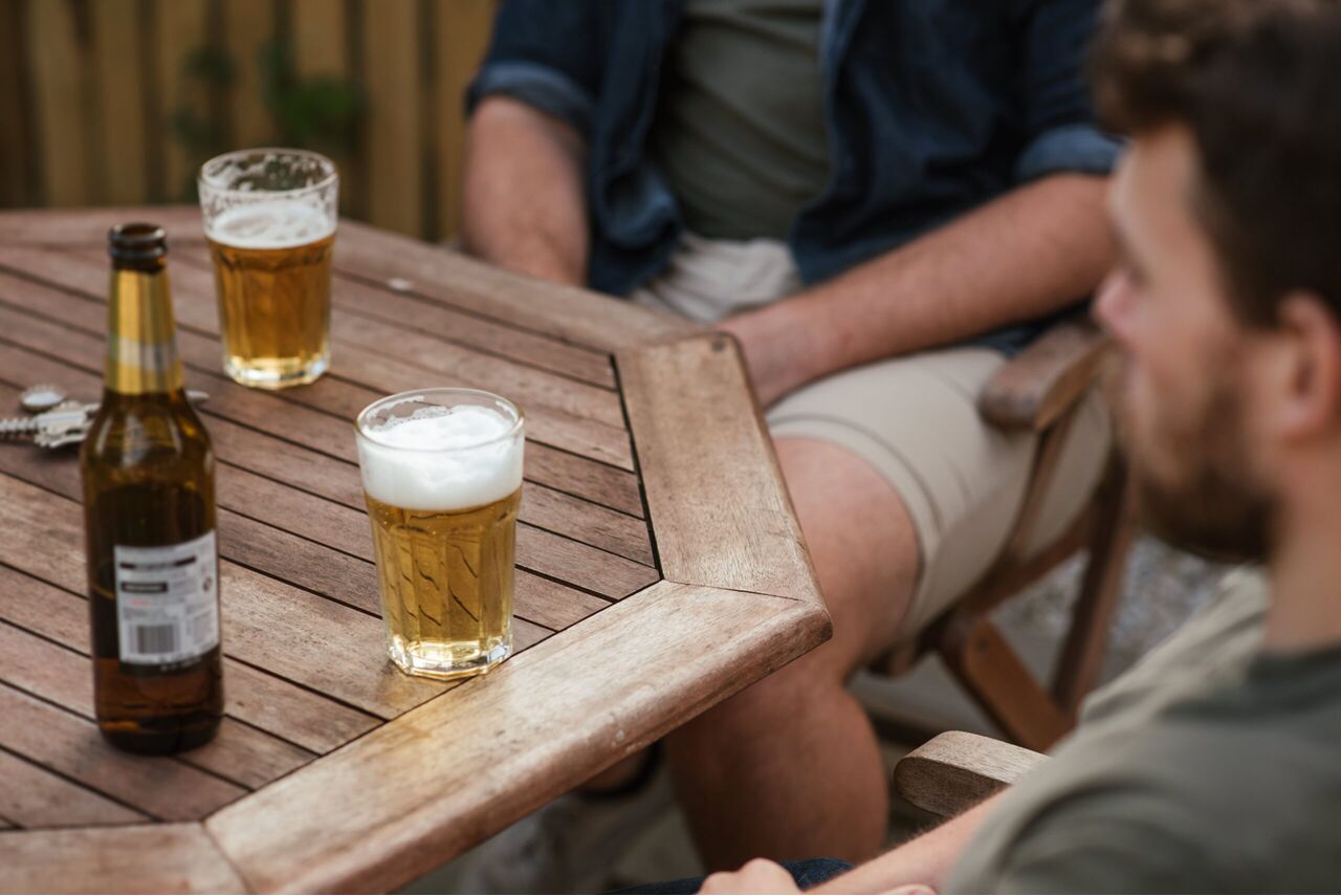 Mannen die aan een tafel bier aan het drinken zijn. 