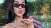 Dua Lipa in bikini, terwijl ze een luchtkusje richting de camera geeft