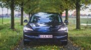 Een Tesla Model 3 rijdt over een bosweg