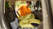 Een man die een slaapzak legt op het luchtbed voor in de auto (te koop bij Lidl)