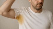 Man met een gele zweetplek onder zijn oksel in zijn t-shirt