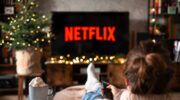 Een vrouw ligt op de bank, afstandsbediening in hand en kijkt Netflix