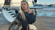 Een vrouw die voor een privéjet staat en een handkusje geeft.