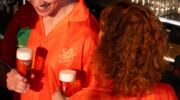 Jongen en meisje dragen een Heineken Pilsjama en houden allebei een biertje vast