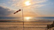 Een zon die ondergaat op een strand met een windmeter.