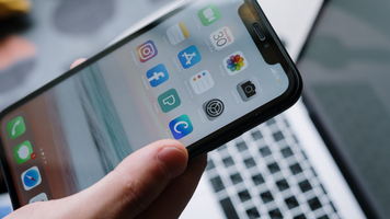 Een iPhone die boven een laptop wordt gehouden.