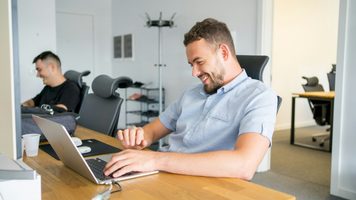 Twee mannen die achter een laptop aan het werk zijn