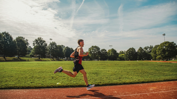 Een man die rent op een atletiekbaan.