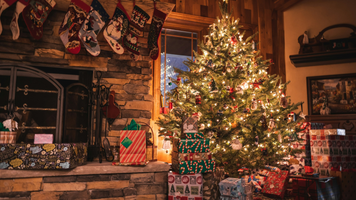 Een kerstboom met cadeautjes in een woonkamer.