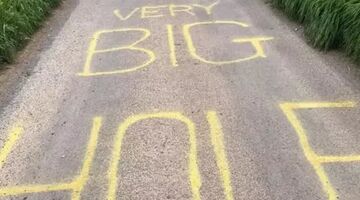 man waarschuwt fietsers voor gat in de weg