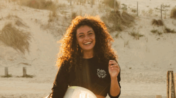 Joël van Leeuwaarde op het strand met surfbord