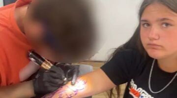De tiener terwijl de wanstaltige tattoo wordt gezet.