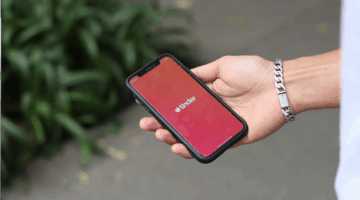 Een man opent de Tinder app, waar binnenkort misschien de lengte-voorkeur functie zal worden geïntroduceerd