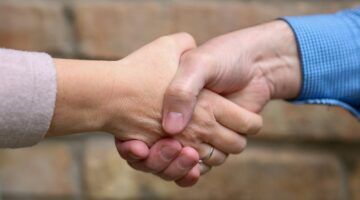 Man en vrouw die elkaar de hand schudden om tot een deal te komen