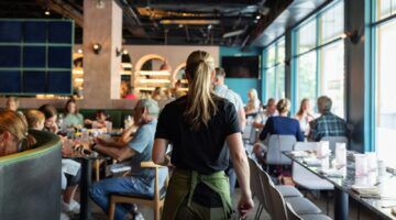 Vrouw die werkt in de horeca, alwaar de lonen flink zijn gestegen.