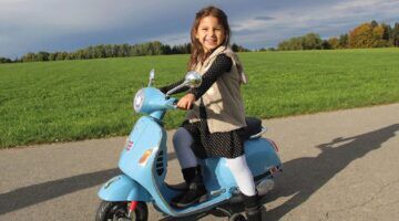 Een kind op de kleine elektrische vespa van de Lidl