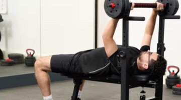 Man die sport op de inklapbare, verstelbare halterbank van Action