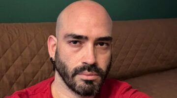 Een kale man met zwarte baard neemt een selfie