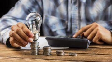 Een man die berekend hoeveel geld hij moet betalen om zijn lampje te laten branden, wat te danken is aan de tariefregels van 2027.