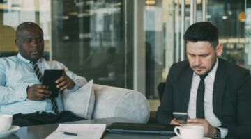 Twee mannen die tijdens het pauze van werk op hun telefoons zitten