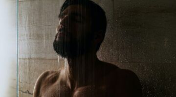 Een man die in een donkere badkamer aan het douchen is