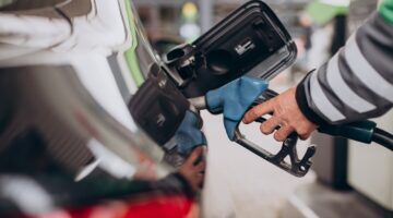 Iemand die benzine tankt aan een tankstation.