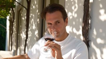 Tobias Camman die ruikt aan een glas wijn.