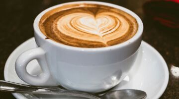 Een kopje koffie op een schoteltje met een lepel.