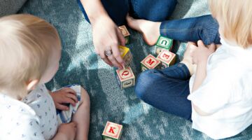 Een moeder die met haar kinderen speelt op een kleedje.