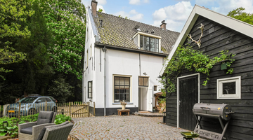 Een wit huis met een zwarte schuur ernaast.