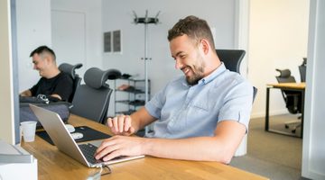 Twee mannen die achter een laptop aan het werk zijn