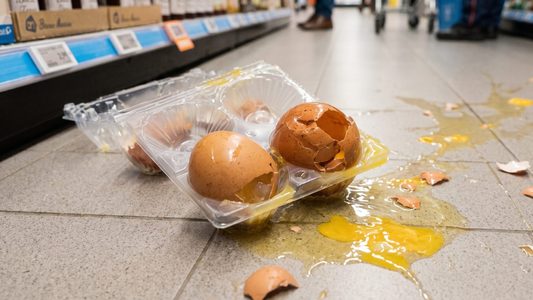 Eieren die stukgevallen zijn op de vloer van een supermarkt