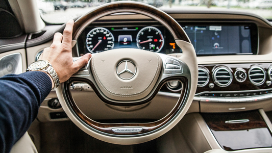 Een man die het stuur van een Mercedes-auto vast heeft.