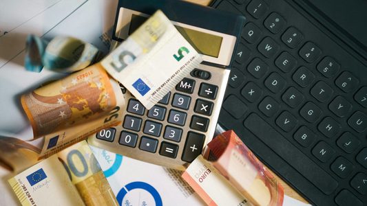 Een stapel geld en een rekenmachine om de kosten van een zorgverekering op uit te rekenen