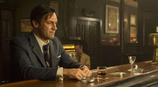 Jon Hamm als Don Draper in Mad Men, hij zit behoorlijk depressief bij een bar